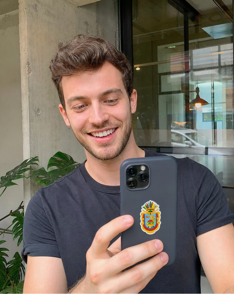Man holding a phone with a colorful emblem on the back, standing indoors.
