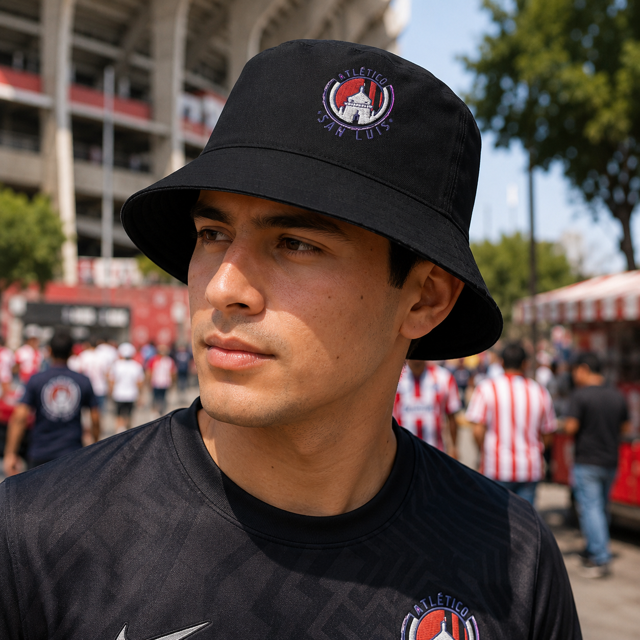 A Mexican model wearing the Atletico San Luis bucket hat in a realistic outdoor lifestyle setting, with the front design clearly visible. The Atletico San Luis bucket hat design, shape, and colors are shown clearly in a natural casual scene.