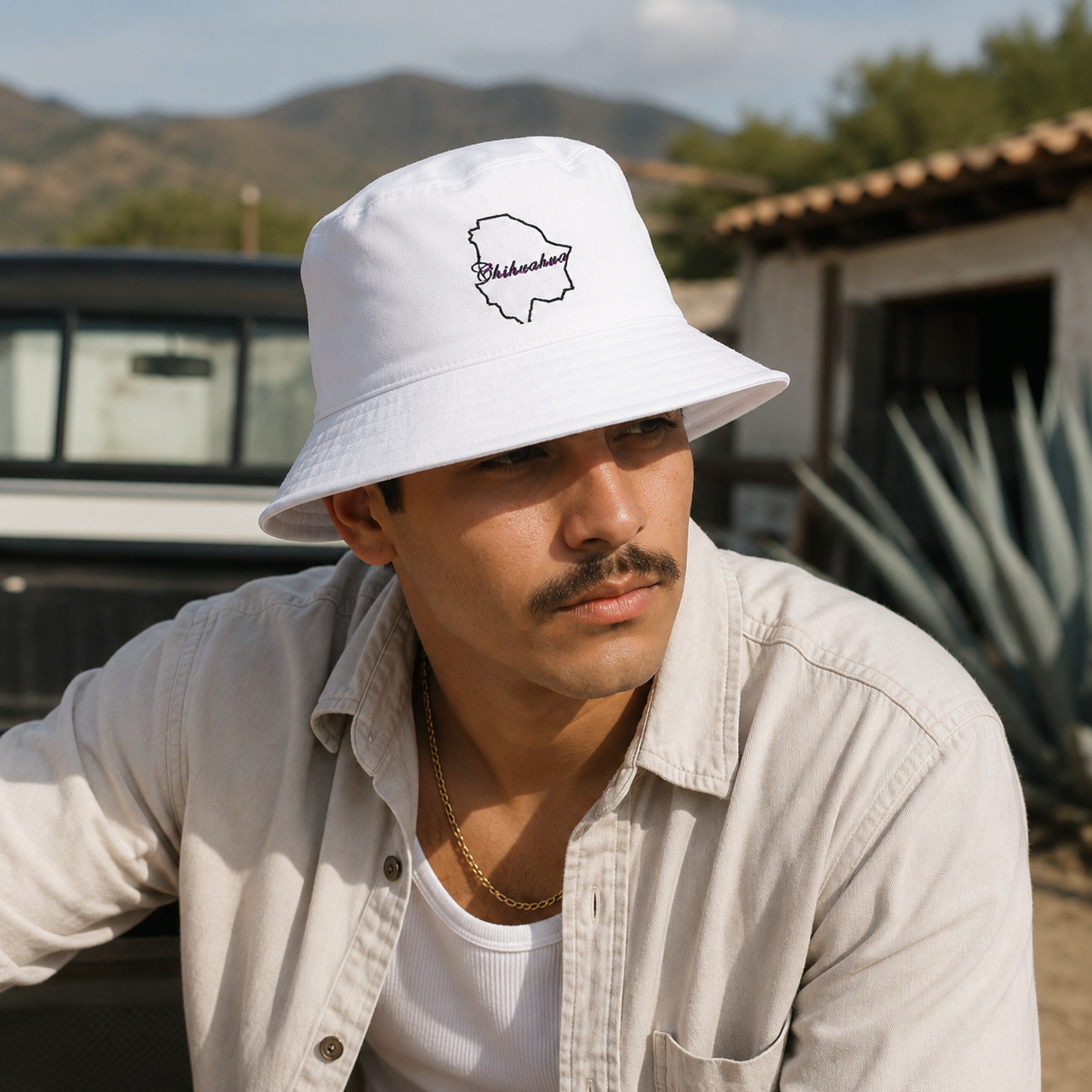 A Mexican model wearing the Chihuahua bucket hat in a realistic outdoor lifestyle setting, with the front design clearly visible. The Chihuahua bucket hat design, shape, and colors are shown clearly in a natural casual scene.