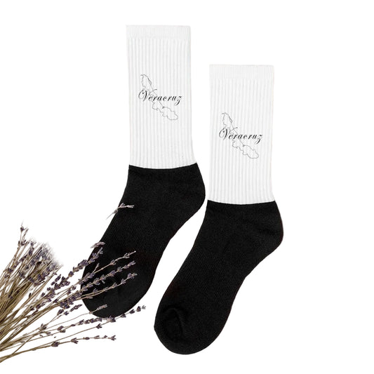 A pair of black and white Veracruz socks with text on the white cuff, displayed on a neutral background with decorative elements.