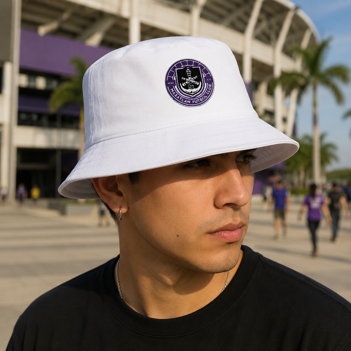 A white bucket hat with the Mazatlan FC logo in the center, featuring a flat brim and a symbol on the front standing outside of a stadium..