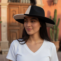 A beige and black two-tone wide brim Panama fedora hat.
