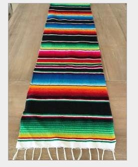 Long multicolor rainbow striped table runner with narrow bands and white fringe at one end.