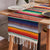 Multicolor rainbow striped table runner with green and yellow bands and white fringe edges.