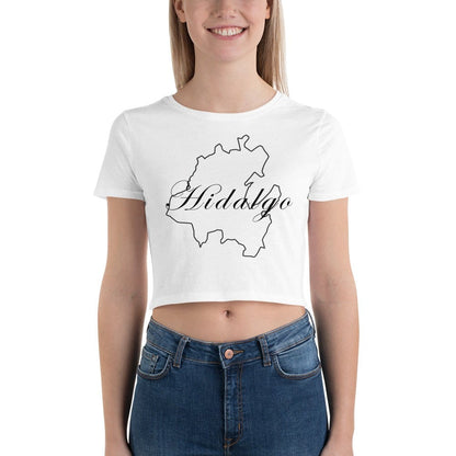 A woman wearing a white crop t-shirt with the text 'Hidalgo' printed in black on the front, paired with blue jeans.