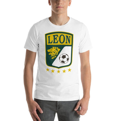 A person wearing a white short-sleeved t-shirt with a Leon graphic print of a soccer team crest. The shirt features a shield with a gold and green design, text, and a soccer ball.
