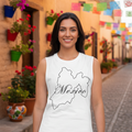 A woman stands on a cobblestone street wearing a white sleeveless tank top with a black outline map of Mexico and the word 'México' printed across the chest. Colorful papel picado banners and potted flowers decorate the background street scene.