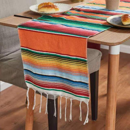 Orange and multicolor rainbow striped table runner with white fringe ends along the sides.