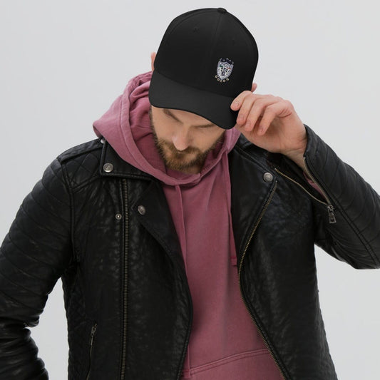A person wearing a black leather jacket and a pink hoodie, adjusting a black baseball cap with a Pachuca FC logo on it.