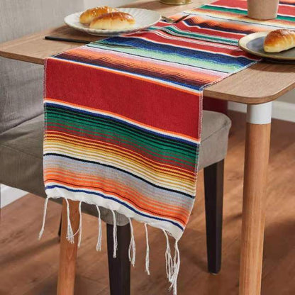 Red rainbow striped table runner with green, blue, orange, yellow bands and white fringe ends.