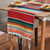 Red rainbow striped table runner with green, blue, orange, yellow bands and white fringe ends.