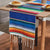 Blue rainbow striped table runner with green, orange, yellow bands and white fringe ends.