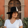 A two-tone wide brim fedora hat with one half beige and the other half black, viewed from the side and from above.