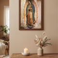 A framed religious art print of Our Lady of Guadalupe hanging on a beige wall above a rustic wooden console table with a lit candle and dried flowers.