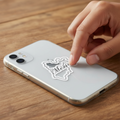 Hand pressing a die-cut bubble-free sticker shaped like the map of Mexico onto a silver smartphone — featuring black cursive text reading “México,” symbolizing national pride and minimalist design.