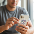 Man seated at a wooden table holding a smartphone with a clear case featuring a die-cut bubble-free sticker of the Club Pachuca logo — a blue and white shield with stars and a monument design, representing the Mexican football team’s heritage.