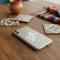 A silver smartphone case with a white outline graphic of a state and the text 'Quintana Roo' resting on a wooden table, surrounded by colorful patterned coasters and a serape blanket.