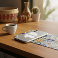 Silver smartphone on a wooden table with a die-cut bubble-free sticker shaped like the state of Chihuahua — featuring white outline and cursive “Chihuahua” text, surrounded by colorful Mexican ceramic tiles, a coffee cup, and decorative figurines, creating a warm, artisanal aesthetic that highlights regional pride and craftsmanship.