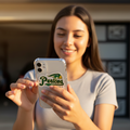 Woman holding smartphone with Pericos de Puebla bubble-free sticker — Gorras Vaqueras vinyl design.