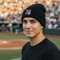 A man wearing a black Sultanes de Monterrey knit beanie with a red, white, and blue 'MLB World Series' logo, standing on a baseball field with a blurred stadium crowd in the background.
