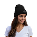 A woman with long brown hair wearing a black knit beanie with a small white Campeche embroidered logo and a white V-neck t-shirt, photographed against a solid white background.