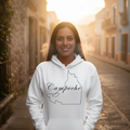 A woman stands on a sunlit cobblestone street wearing a white hoodie with a black outline graphic of the Guatemalan map and the word 'Campeche' across the front.
