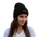 A woman with long brown hair wearing a black knit beanie with a white embroidered mountain logo and the word 'Chiapas' on the front, paired with a white v-neck t-shirt against a solid white background.