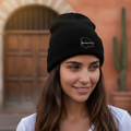 A woman wearing a black beanie hat with an embroidered design of a Chihuahua.