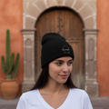 A woman wearing a black beanie hat with an embroidered design on the front.