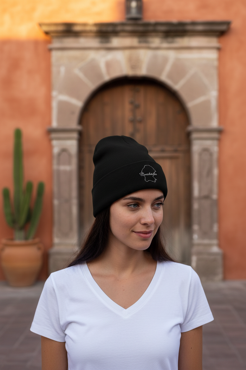A woman wearing a black beanie hat with an embroidered design on the front.