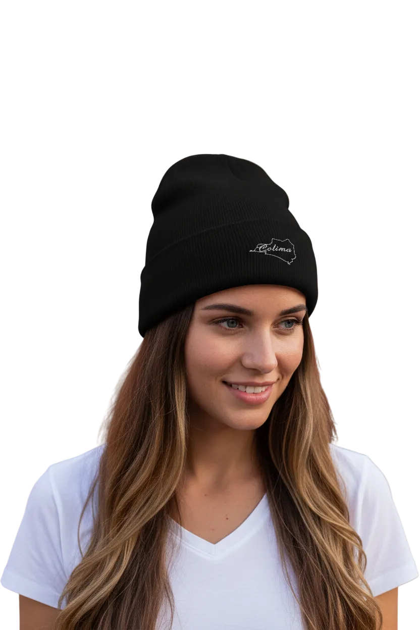 A woman with long brown hair wearing a black knit beanie with a white embroidered Colima logo, paired with a white t-shirt, set against a solid white background.