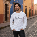 A person wearing a white long-sleeved crew neck t-shirt with the text 'Colima' on it, in an Athletic Heather color.