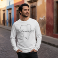 A man wearing a white long-sleeve crewneck sweatshirt with a black outline map of Durango and the word 'Durango' written across it, standing on a cobblestone street in front of colorful buildings.