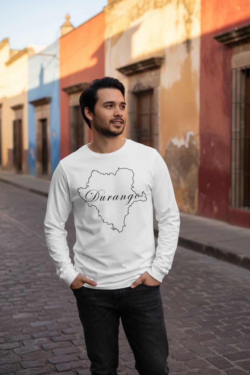 A man wearing a white long-sleeve crewneck sweatshirt with a black outline map of Durango and the word 'Durango' written across it, standing on a cobblestone street in front of colorful buildings.