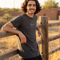 A person wearing a black Guanajuato unisex denim t-shirt with a graphic on the front.