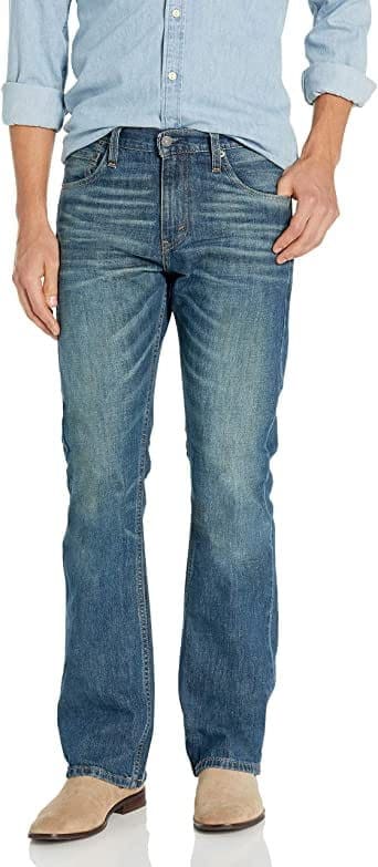 A pair of Levi's men's slim bootcut fit jeans in blue color, displayed on a model with a light blue shirt and beige shoes.