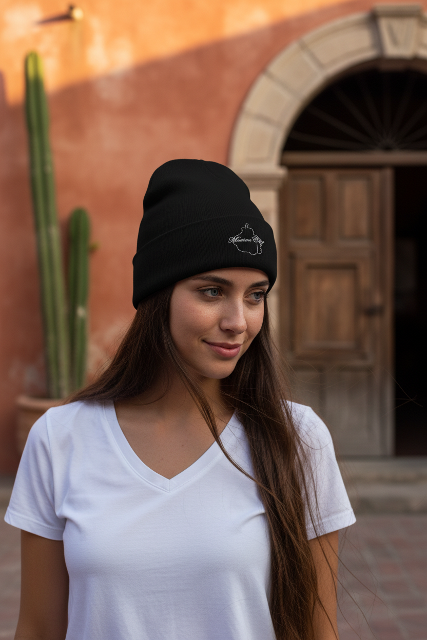 A person wearing a black beanie hat with an embroidered design on the front.
