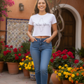 A woman wearing a white crop t-shirt with the text 'Nuevo León' on the front, paired with blue jeans.