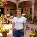 A woman wearing a white crop t-shirt with 'Oaxaca' text on it, paired with blue jeans.