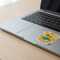 A die cut bubble free sticker with the official coat of arms of Coahuila, predominantly yellow with a depiction of a tree and the text 'COAHUILA DE ZARAGOZA'. on topof a Macboo.
