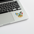 A sticker with the official coat of arms of Hidalgo, featuring a blue and white shield with a mountain, a helmet, and a golden emblem, applied next to the trackpad of a Macbook Pro.