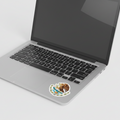 Sticker with the Official Coat of Arms of Mexico design, featuring an eagle with a snake in its beak, surrounded by a wreath applied next to the track pad of a laptop.