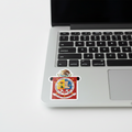 A die cut bubble-free sticker featuring the official coat of arms of Oaxaca. The sticker is white with a graphical design, including a emblem and text, and measures 3 inches by 3 inches next to the trackpad of a MacBook Pro..