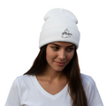 A woman wearing a white knit beanie with a black embroidered logo that reads 'The Philosopher' and a small fish icon, paired with a white V-neck t-shirt against a plain white background.