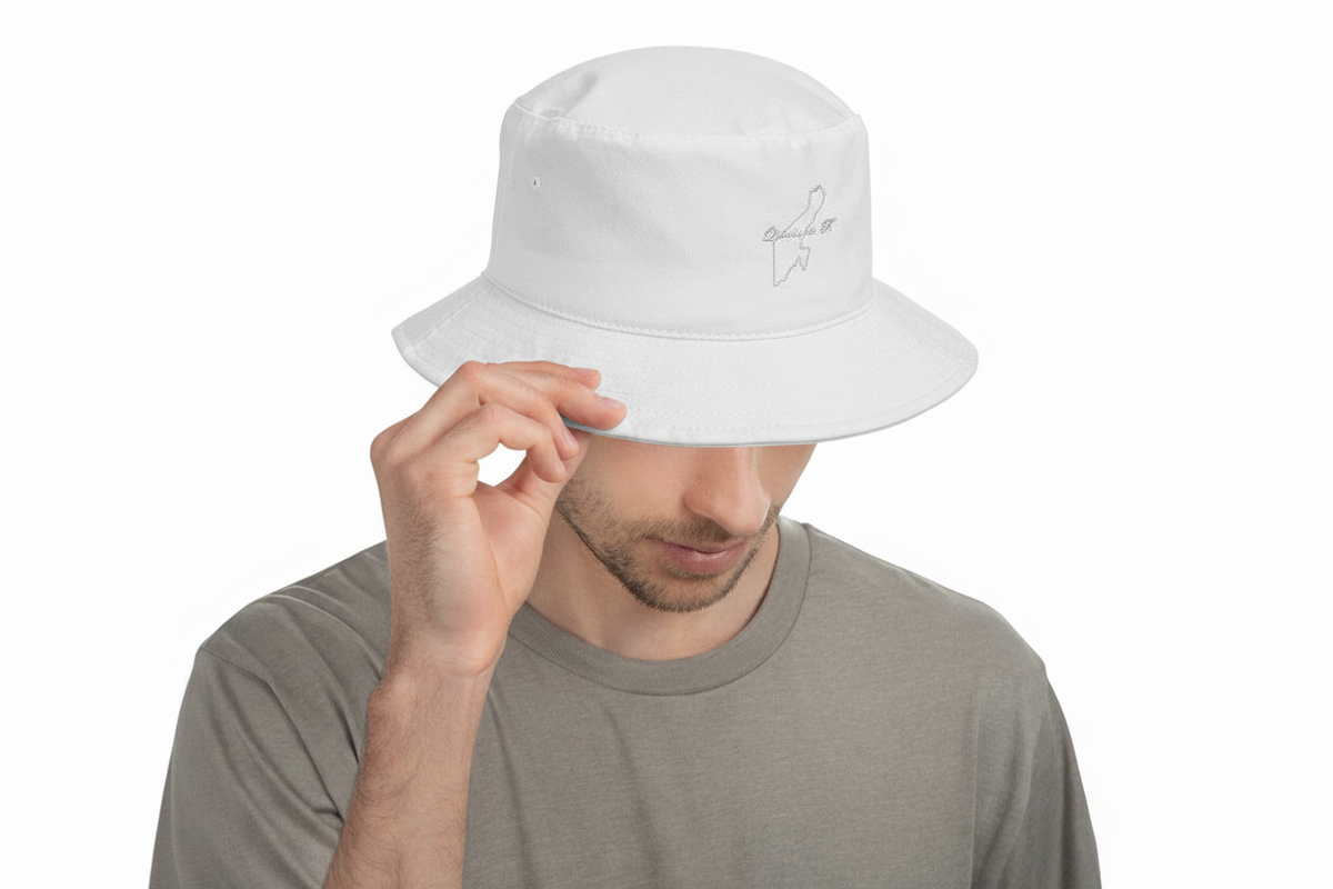 A man wearing a white Quintana Roo bucket hat with a small gray embroidered logo on the side, holding the brim with one hand against a plain white background.