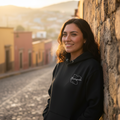 A black unisex hoodie with a graphic design on the front, displayed on a hanger.