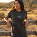 A woman wearing a black short-sleeved denim t-shirt with text on the front.
