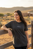 A woman wearing a black denim t-shirt with the Tabasco logo on the chest.