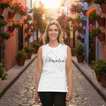 A woman stands on a cobblestone street wearing a white sleeveless tank top with a black outline map of Salina, Colorado, and the word 'Salina' printed across the chest. The background shows a sunlit narrow street lined with colorful flower boxes and buildings.