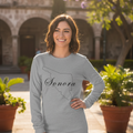 A woman wearing a gray long sleeve t-shirt with the text 'Sonora' on it.